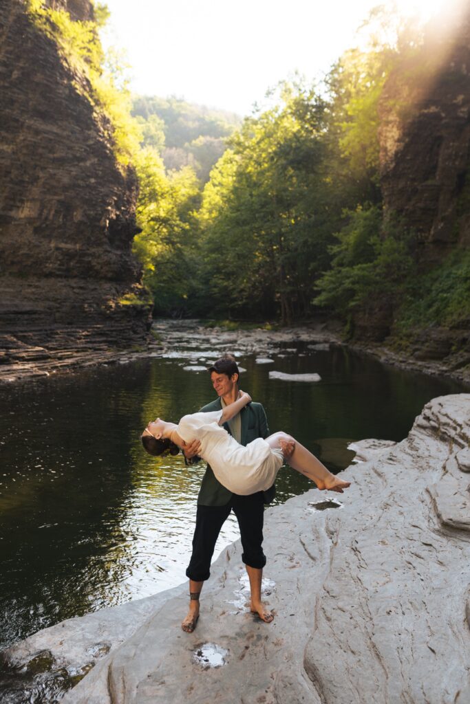 newlyweds embracing each other at the base of a waterfall at Robert H. Treman State Park in upstate new york