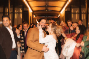 a married couple kisses among a crowd of guests