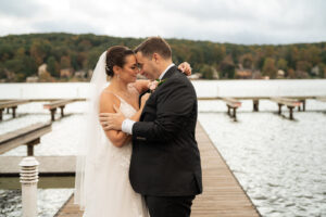 a bride and groom holding each other on a marina dock lakeside