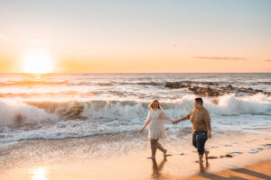 a gay couple strolls on the jersey shore during sunrise