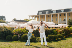 a couple wearing chic summer clothes infront of white umbrellas by a shore town