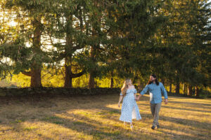 a couple walks through a forest at golden hour