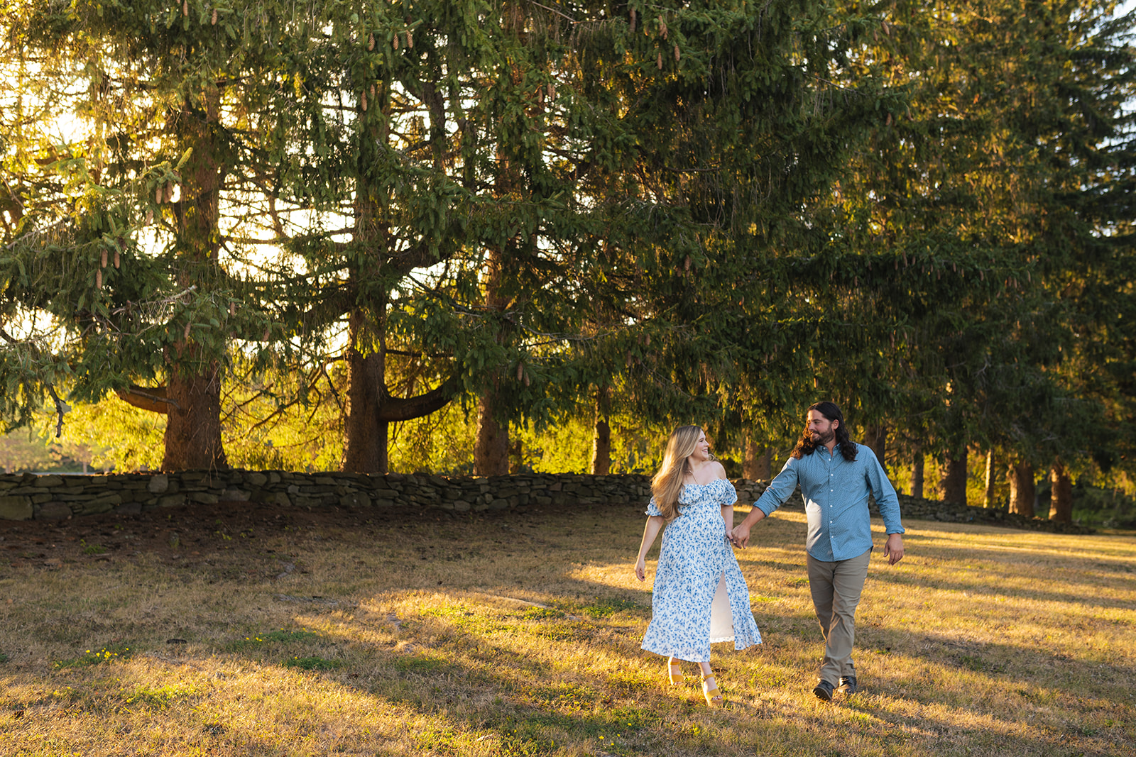 a couple walks through a forest at golden hour