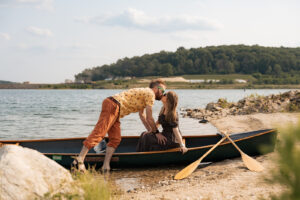 a man reaches down to kiss a woman in a canoe on a summer day