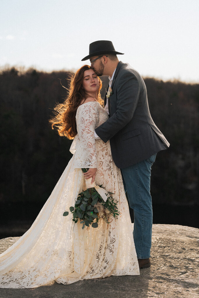 a bride and groom kiss each other on a mountaintop