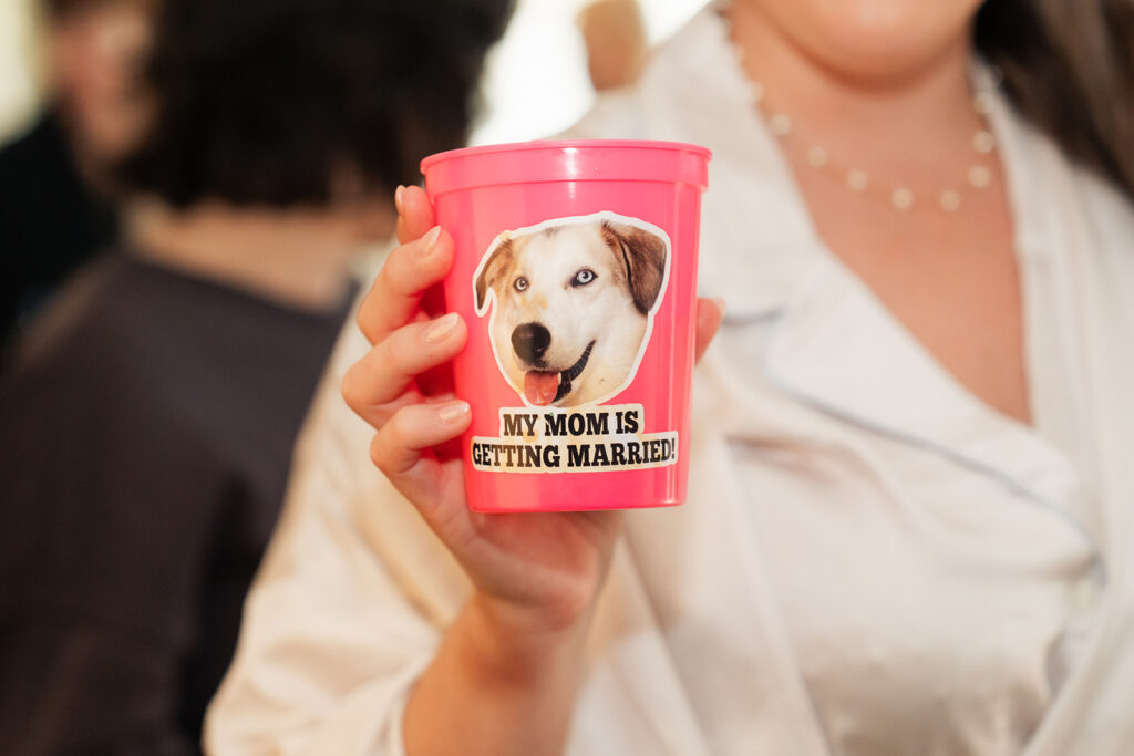 a bride holding a pink cup with her dog's face on it