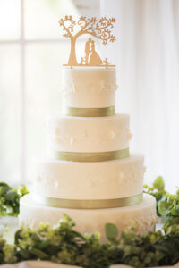 a wedding cake with a silhouette cake topper of the couple with their cat and dog