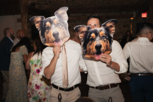 two people holding up big cardboard cut outs of a dog's face at a wedding reception