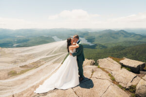 a bride and groom kiss on top of whiteface mountain 