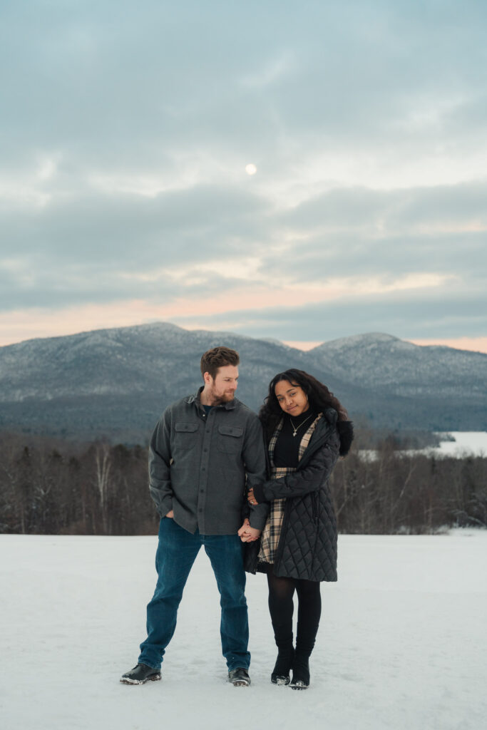 a couple standing in front of vermont mountains during a winter sunset