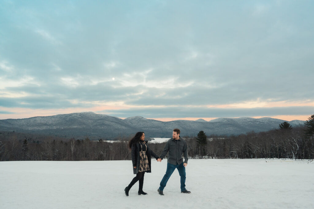 a couple standing in front of vermont mountains during a winter sunset