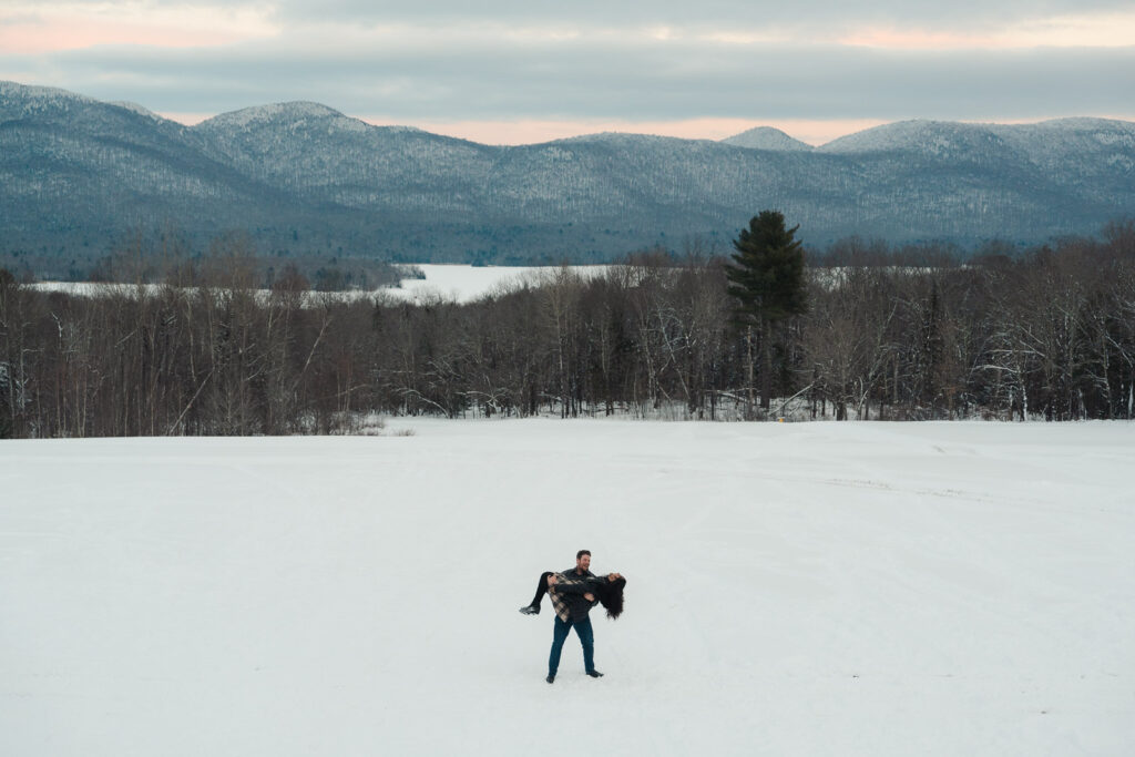 a couple standing in front of vermont mountains during a winter sunset