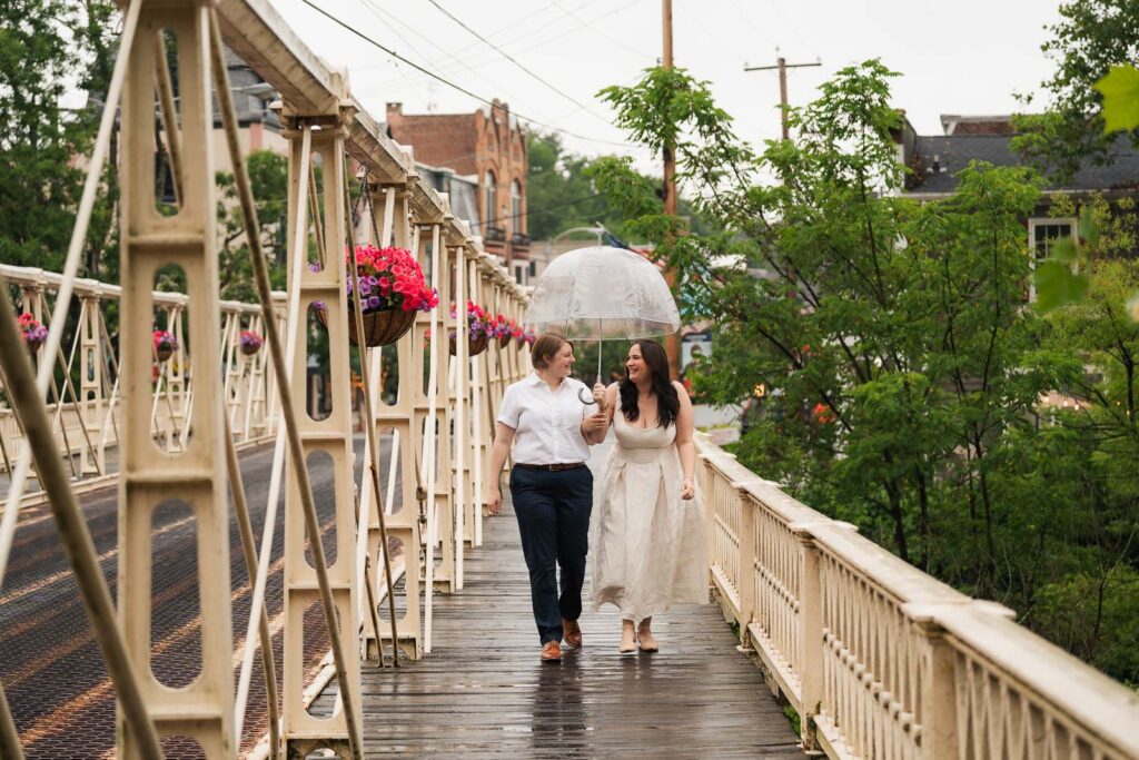 Couple walking under an umbrella on rainy Main Street in Clinton NJ during engagement session