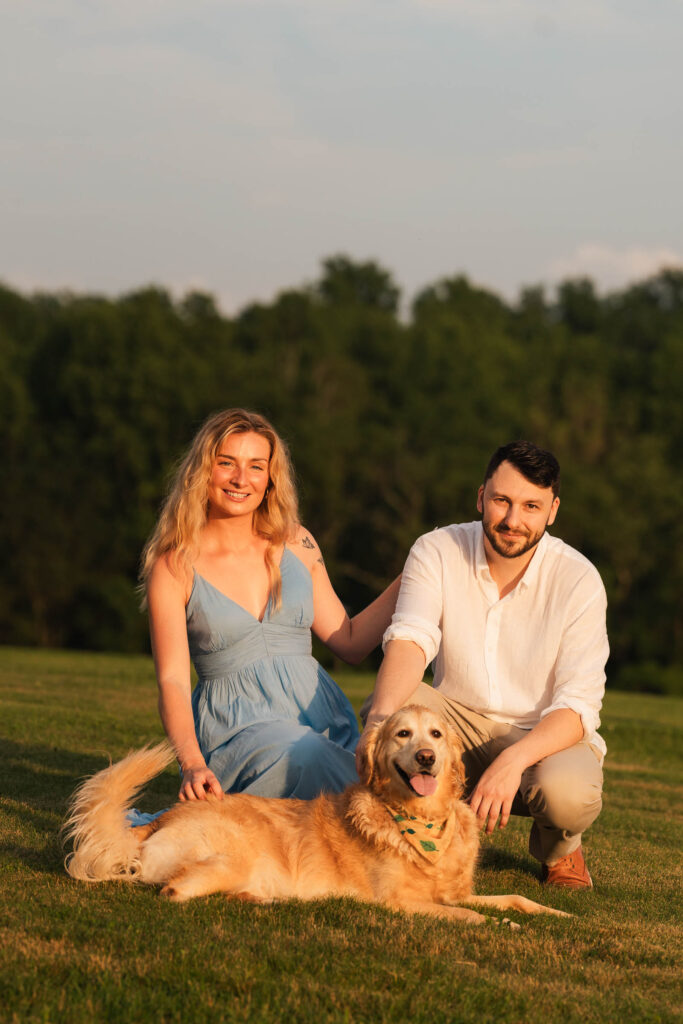 engaged couple with their golden dog at golden hour