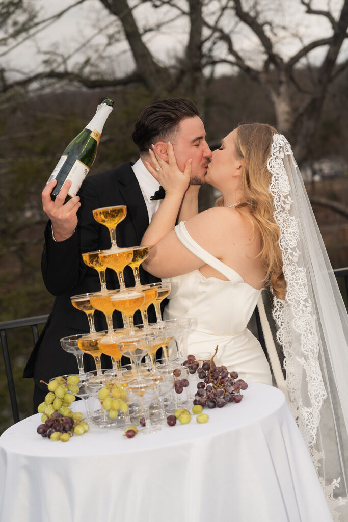 bride and groom kiss by their champagne tower in the Poconos.