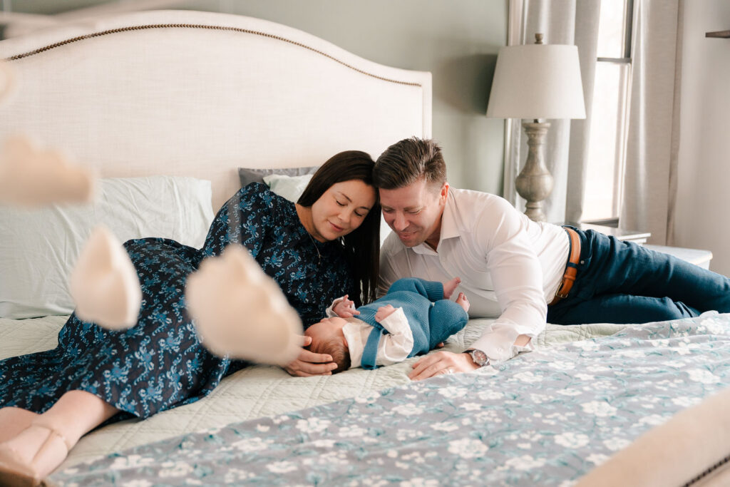 A mom and father hold their newborn for an intimate newborn photography session.