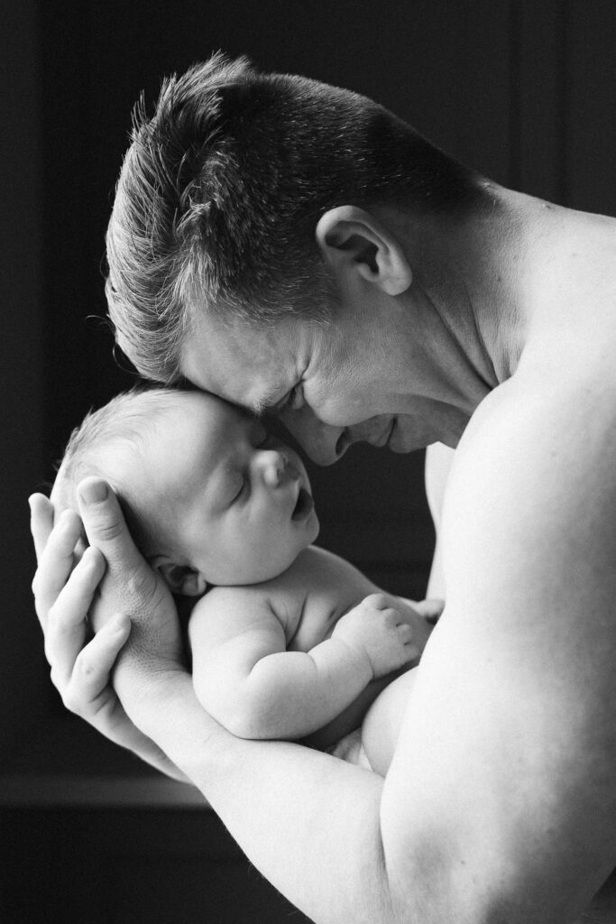 A mom and father hold their newborn for an intimate newborn photography session.