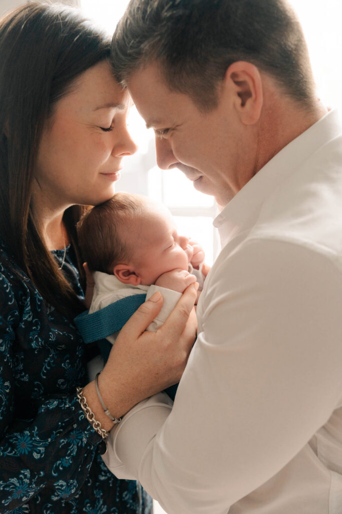 A mom and father hold their newborn for an intimate newborn photography session.