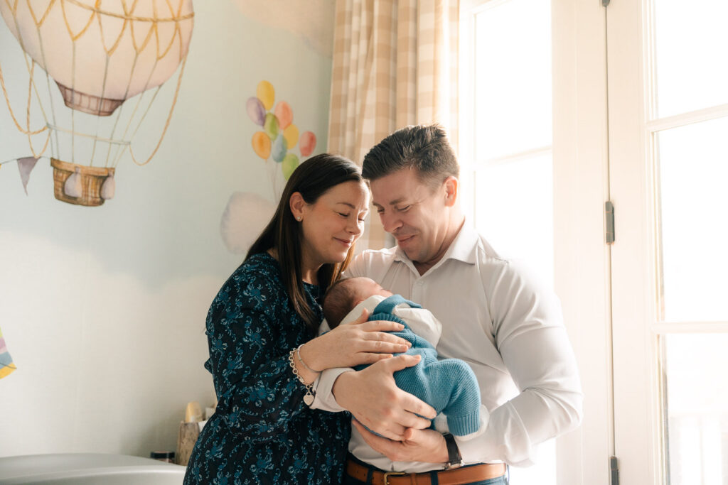A mom and father hold their newborn for an intimate newborn photography session.