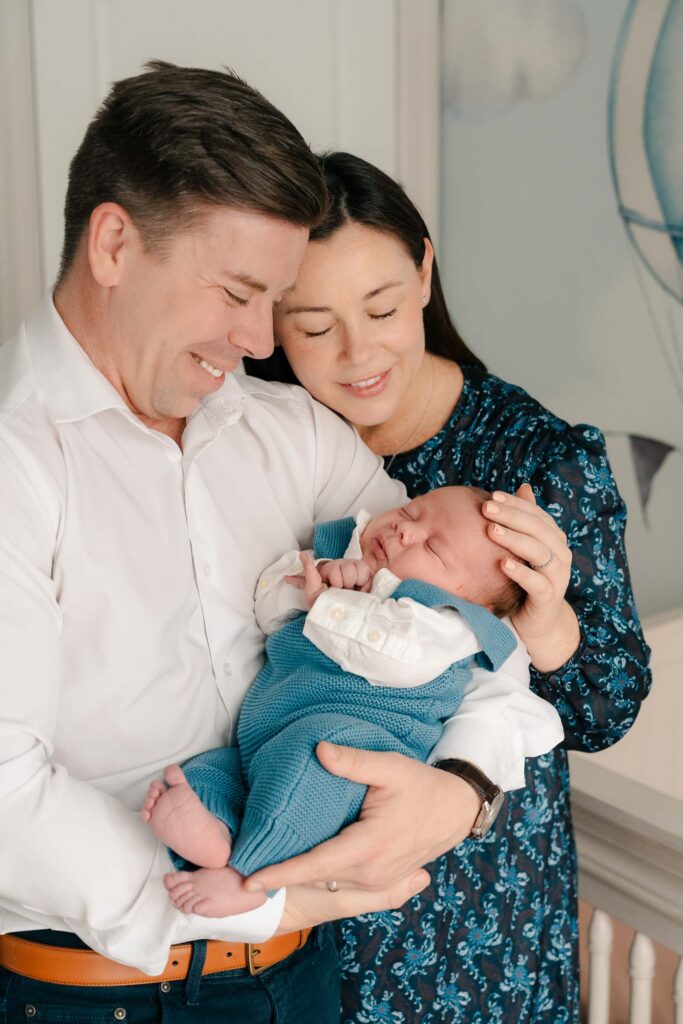 A mom and father hold their newborn for an intimate newborn photography session.