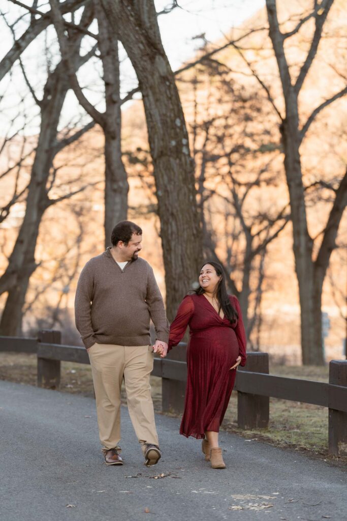 A winter maternity session at Bear Mountain State Park near Bear Mountain Inn, featuring golden hour light, a red dress, and a couple expecting their baby boy.