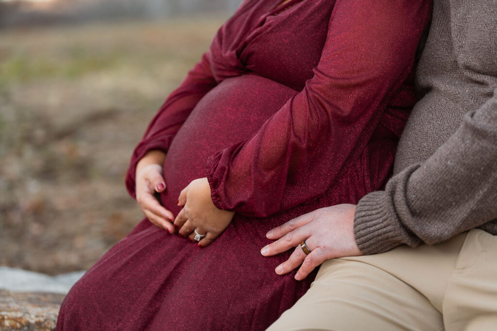 A winter maternity session at Bear Mountain State Park near Bear Mountain Inn, featuring golden hour light, a red dress, and a couple expecting their baby boy.