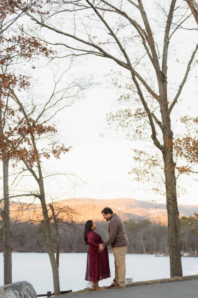 A winter maternity session at Bear Mountain State Park near Bear Mountain Inn, featuring golden hour light, a red dress, and a couple expecting their baby boy.