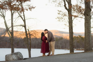 A winter maternity session at Bear Mountain State Park near Bear Mountain Inn, featuring golden hour light, a red dress, and a couple expecting their baby boy.