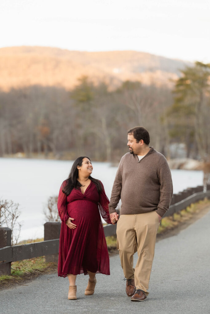 A winter maternity session at Bear Mountain State Park near Bear Mountain Inn, featuring golden hour light, a red dress, and a couple expecting their baby boy.