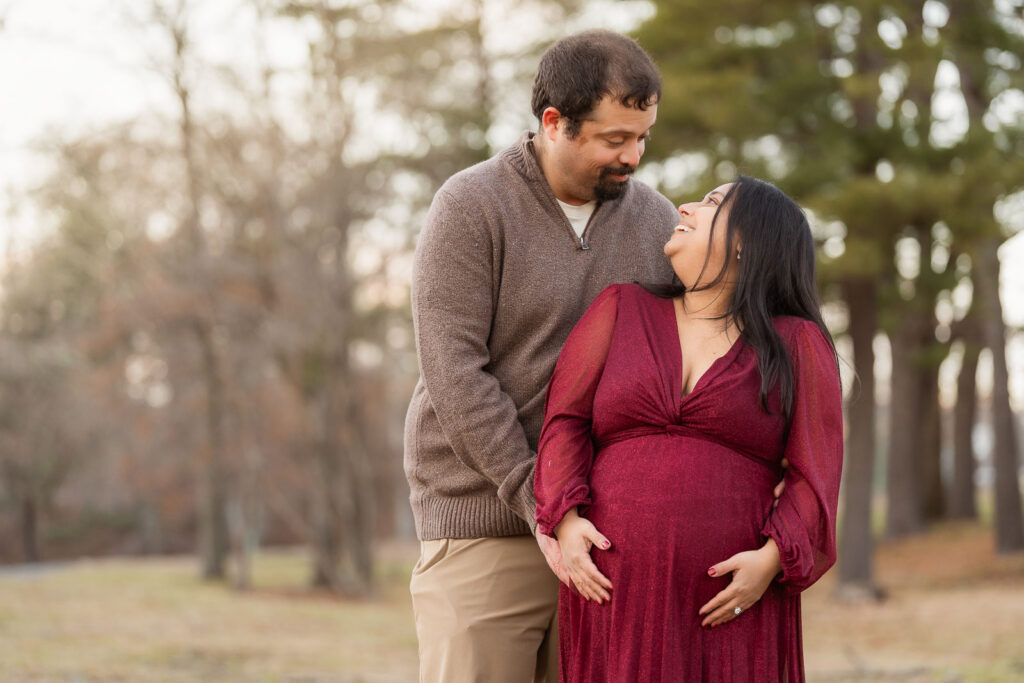 A winter maternity session at Bear Mountain State Park near Bear Mountain Inn, featuring golden hour light, a red dress, and a couple expecting their baby boy.