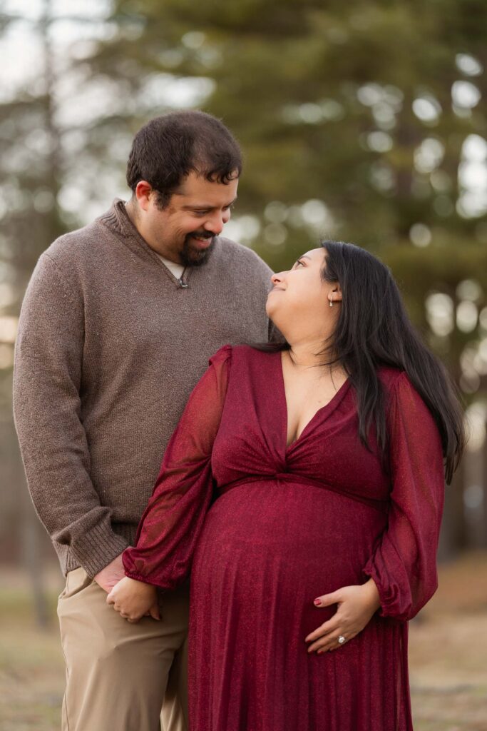 A winter maternity session at Bear Mountain State Park near Bear Mountain Inn, featuring golden hour light, a red dress, and a couple expecting their baby boy.