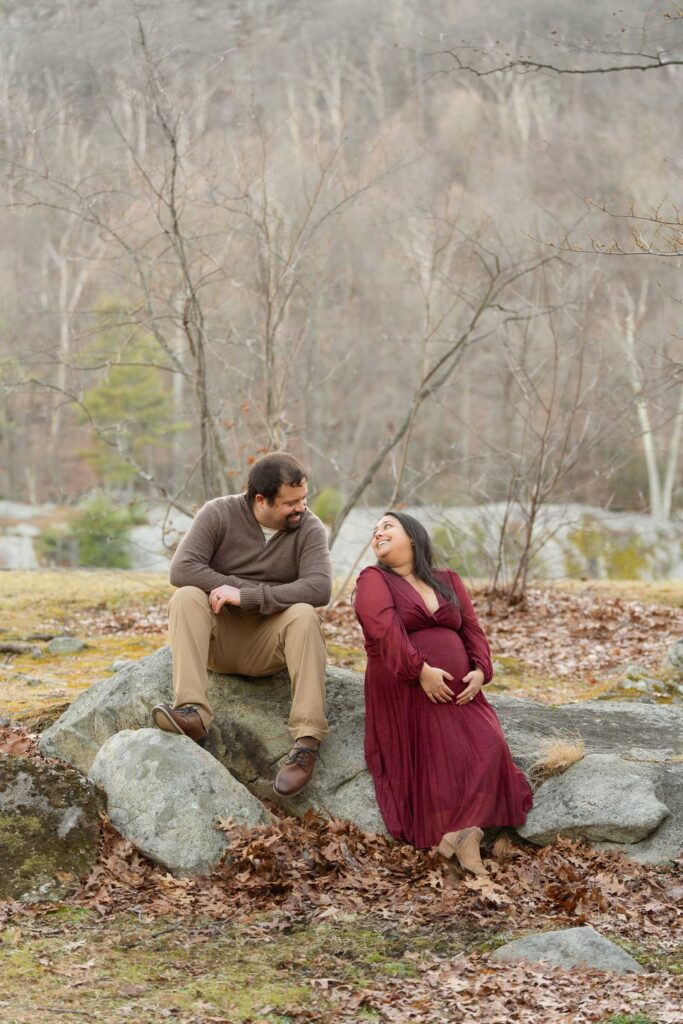 A winter maternity session at Bear Mountain State Park near Bear Mountain Inn, featuring golden hour light, a red dress, and a couple expecting their baby boy.