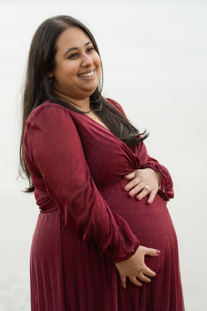 A winter maternity session at Bear Mountain State Park near Bear Mountain Inn, featuring golden hour light, a red dress, and a couple expecting their baby boy.