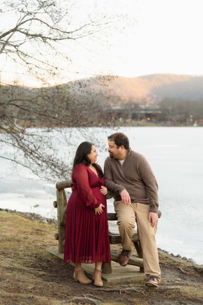 A winter maternity session at Bear Mountain State Park near Bear Mountain Inn, featuring golden hour light, a red dress, and a couple expecting their baby boy.