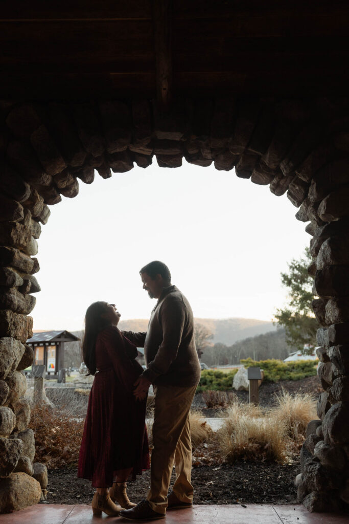 A winter maternity session at Bear Mountain State Park near Bear Mountain Inn, featuring golden hour light, a red dress, and a couple expecting their baby boy.