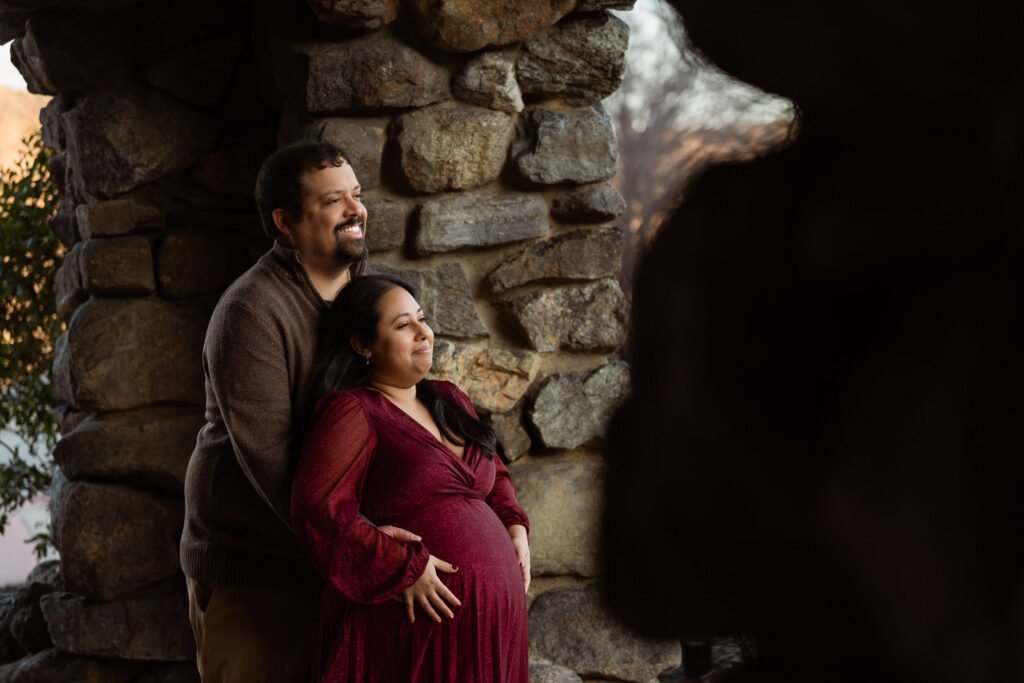A winter maternity session at Bear Mountain State Park near Bear Mountain Inn, featuring golden hour light, a red dress, and a couple expecting their baby boy.