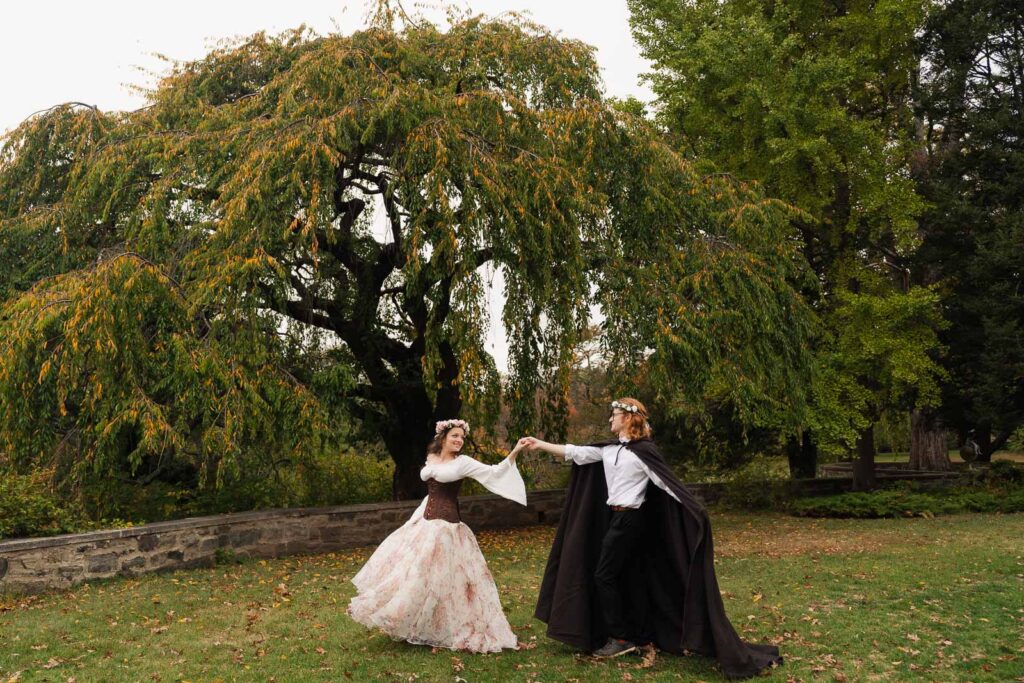 A Renaissance-inspired autumn engagement session at Skylands Manor and the New Jersey Botanical Gardens in Ringwood, NJ, featuring flower crowns, a wool cape, and romantic garden portraits before a Stone House wedding.