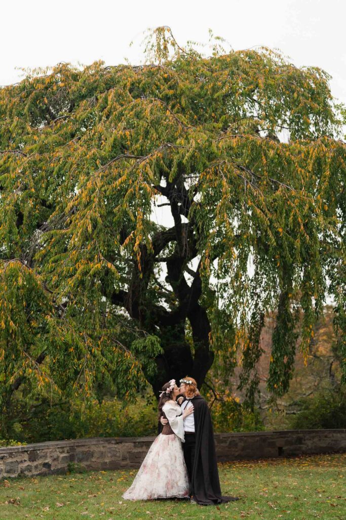 A Renaissance-inspired autumn engagement session at Skylands Manor and the New Jersey Botanical Gardens in Ringwood, NJ, featuring flower crowns, a wool cape, and romantic garden portraits before a Stone House wedding.